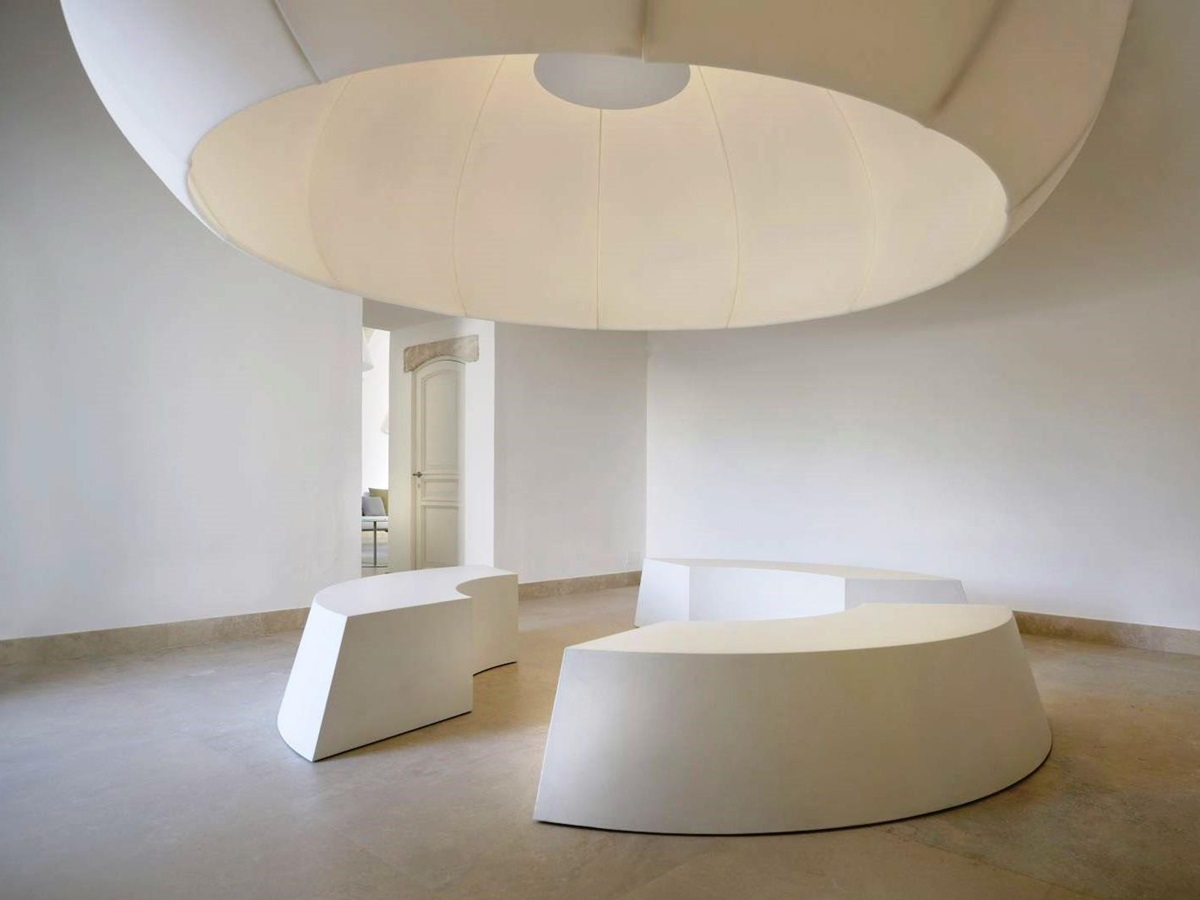 Big white Eden masterpiece XXXL lamp, above 3 white curved seats at villa masseria dei papi in Puglia, Italy