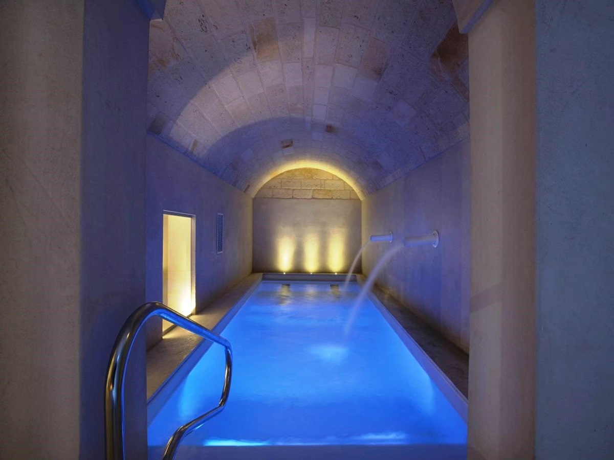 Indoor pool in spa with curved stone ceiling and 2 water fountains coming out of wall at villa masseria dei papi in Puglian, Italy