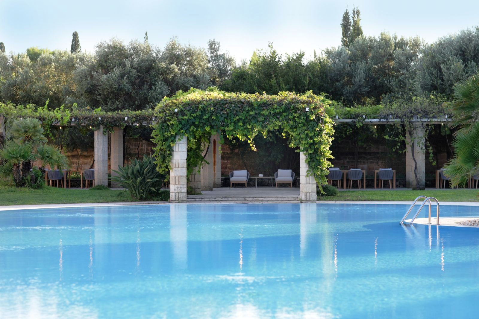 View over swimming pool to vine covered pergola at villa masseria dei papi in Puglian, Italy