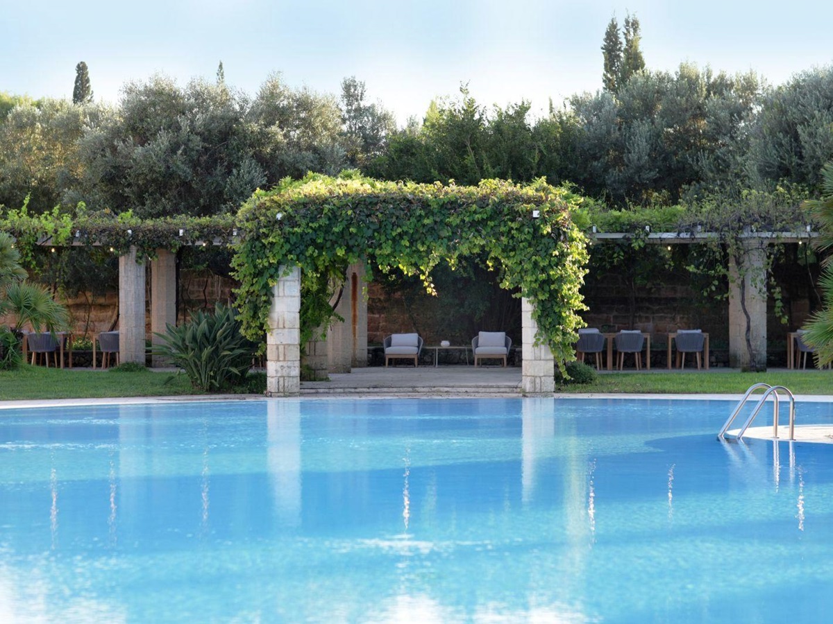 View over swimming pool to vine covered pergola at villa masseria dei papi in Puglian, Italy