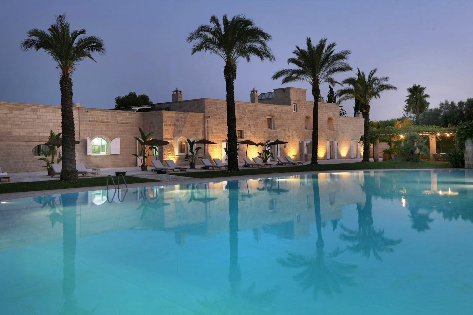 View over pool at sunset of the exterior of villa masseria dei papi in Puglian, Italy