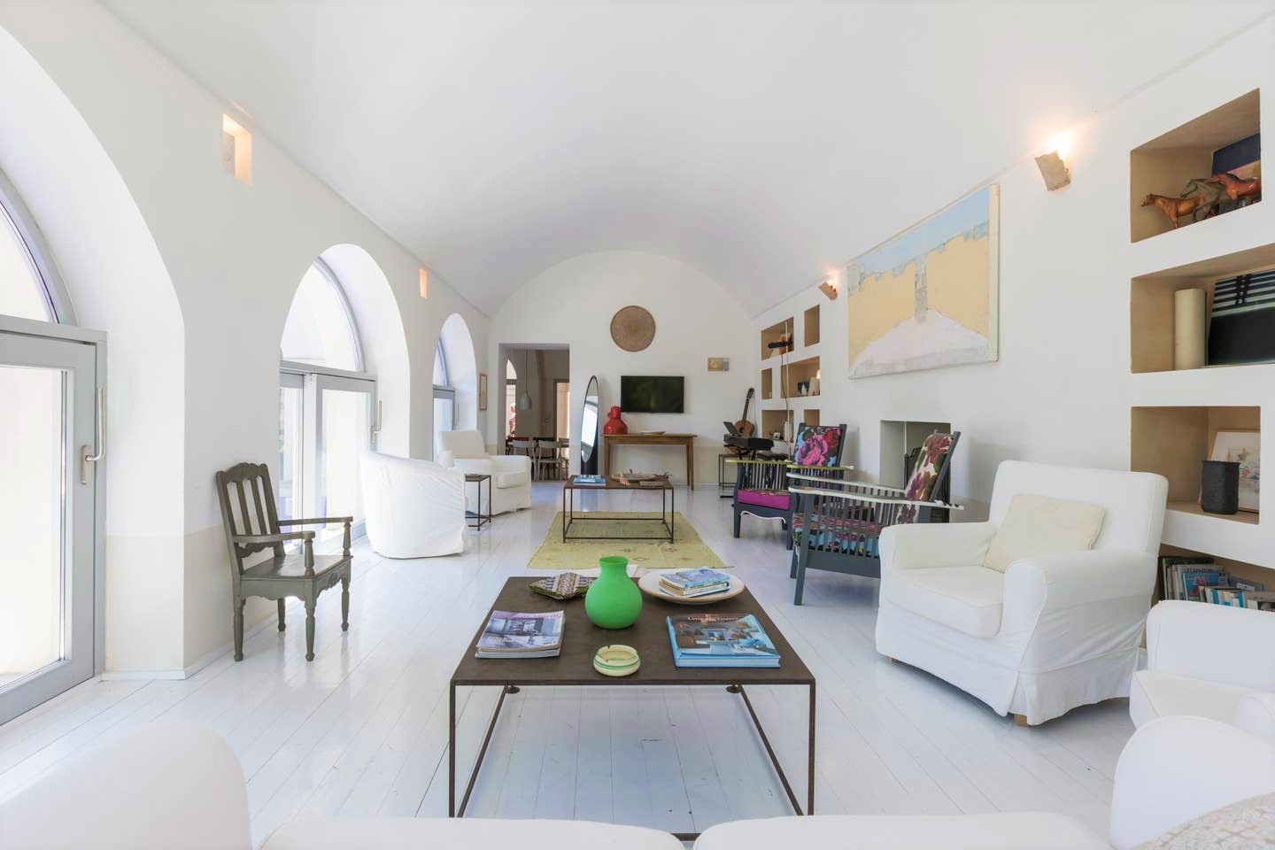 Living room with sofa, armchairs, coffee tables, chairs, painting, shelves and TV at Palazzo del Duca in Puglia, Italy