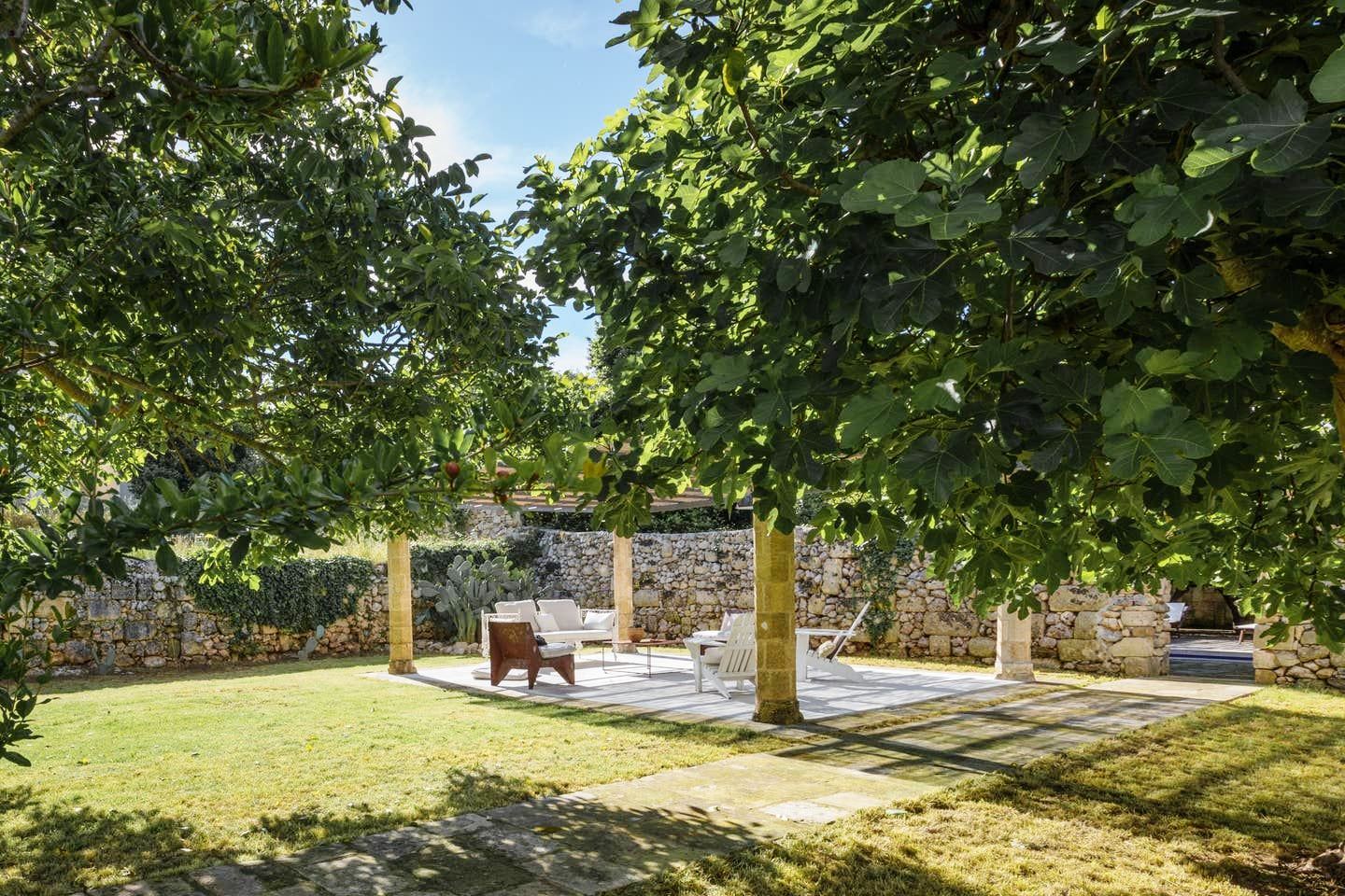 chairs and table under the trees at luxury villa palazzo del duca in puglia, italy 