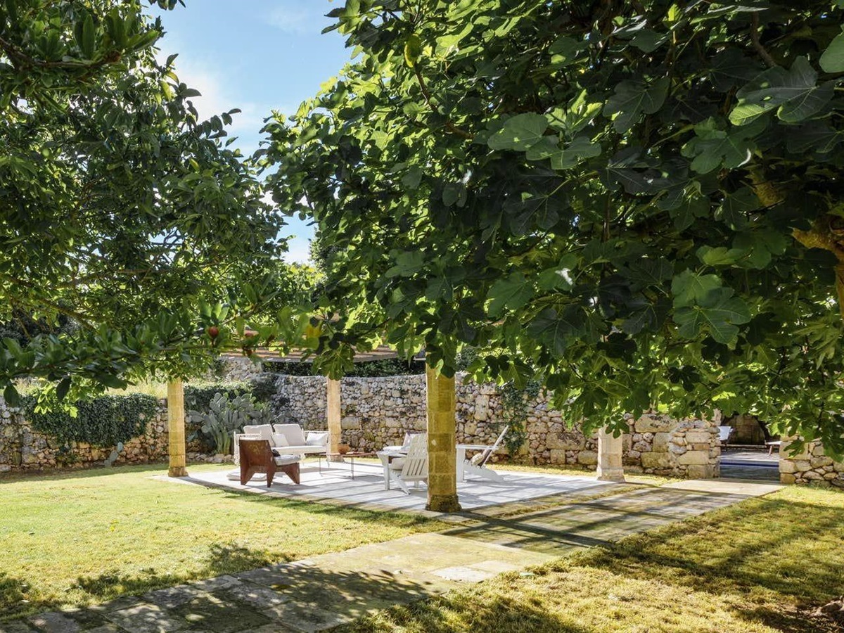 chairs and table under the trees at luxury villa palazzo del duca in puglia, italy