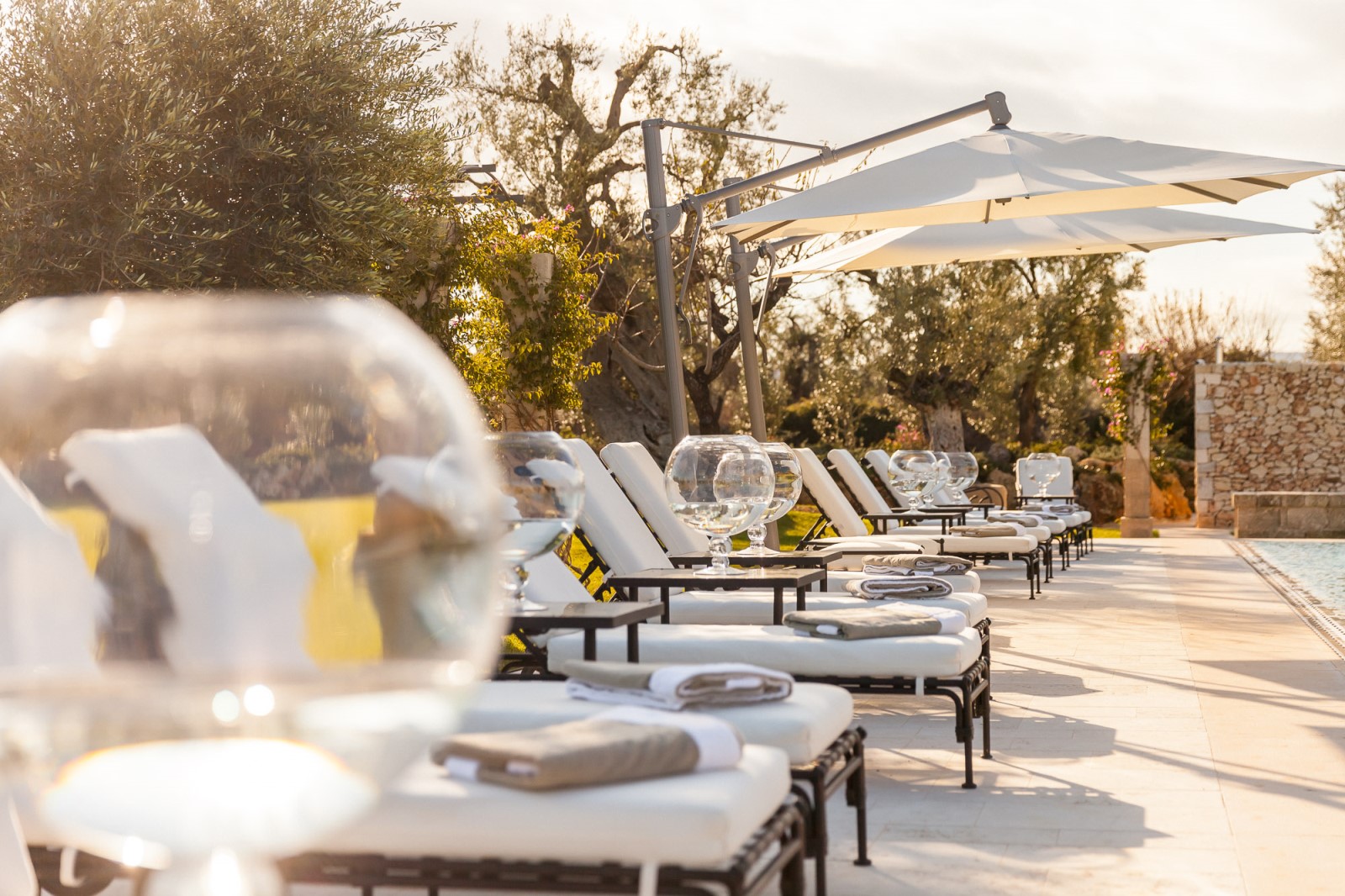 The sun loungers with wine glasses at the swimming pool of Residenza Pettolecchia, Puglia