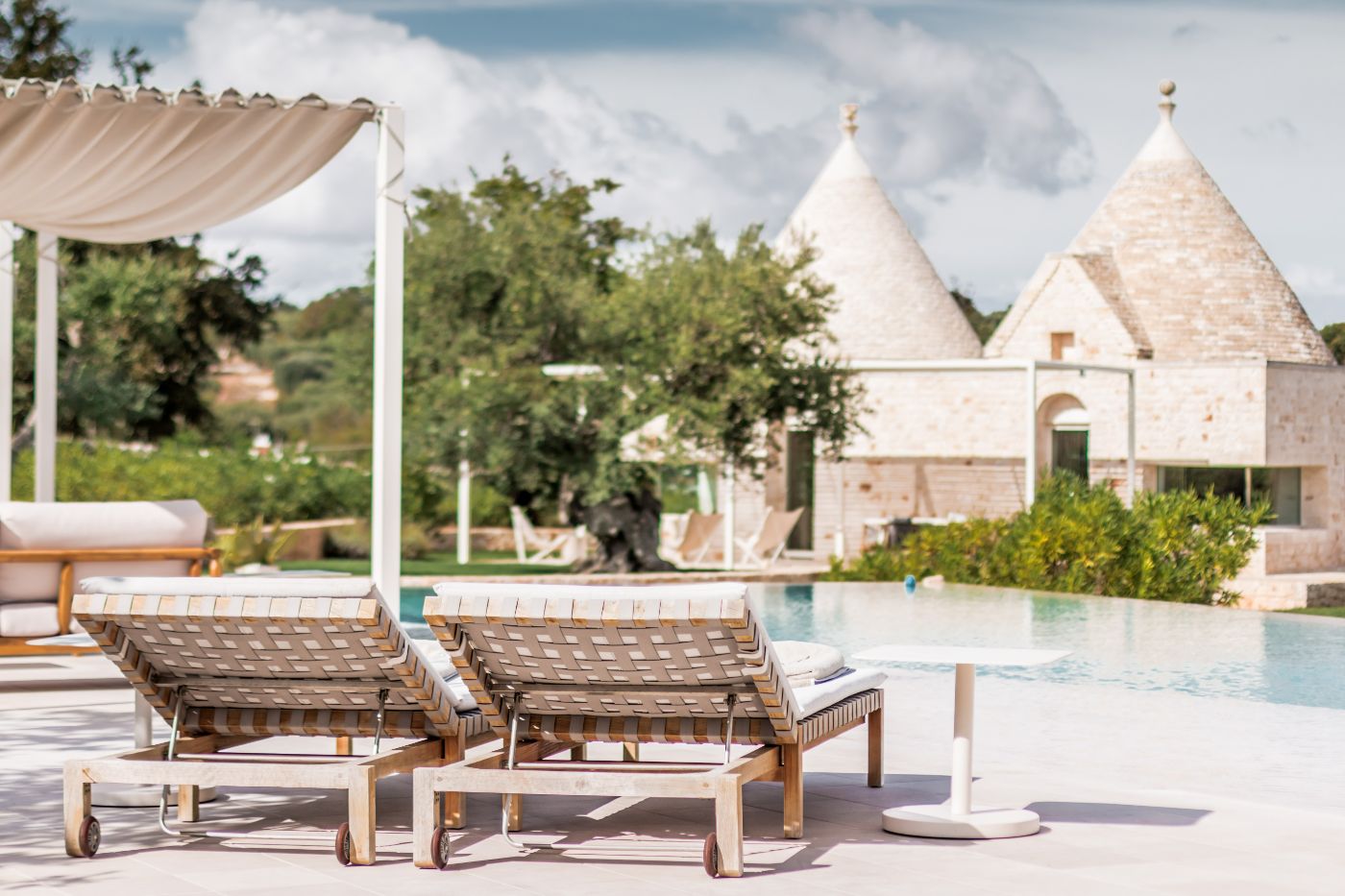 Pool loungers and a view of the trullis at Trulli Bianca.