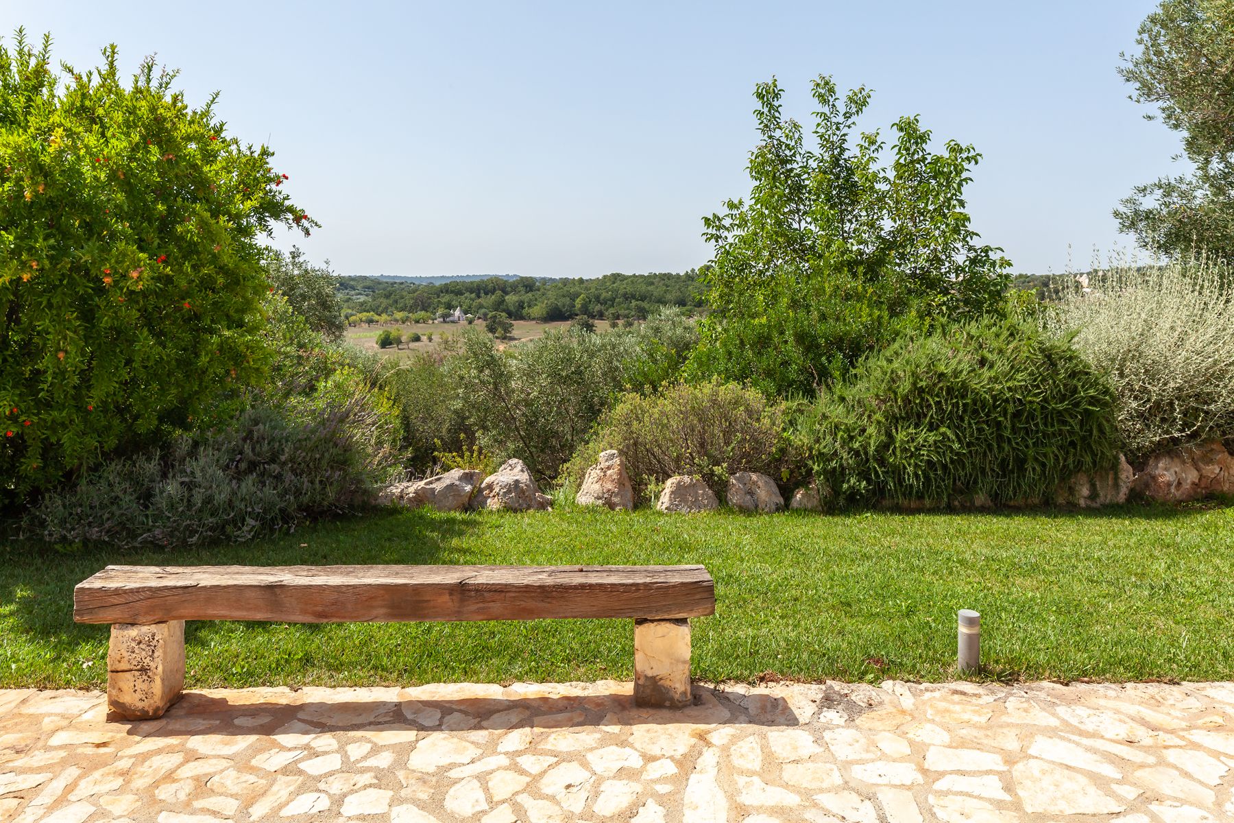 Garden views with wooden bench at Trulli Lucia in Puglia