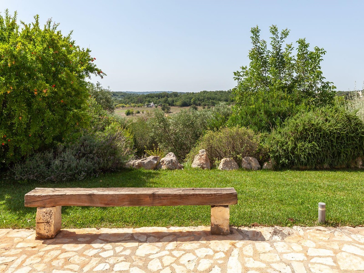 Garden views with wooden bench at Trulli Lucia in Puglia