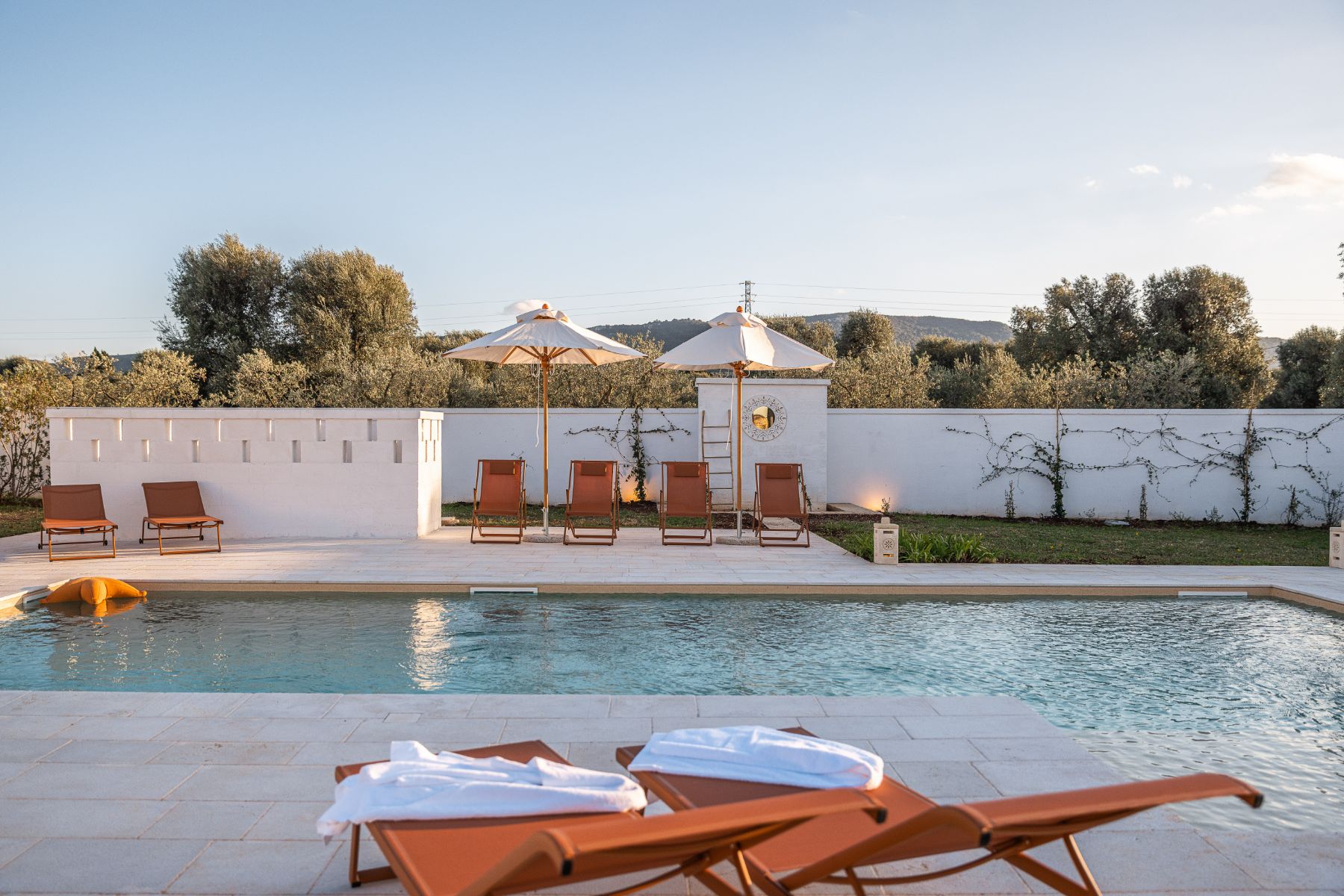 Pool area at Villa Oliva in Puglia with view of sunloungers and trees in the background