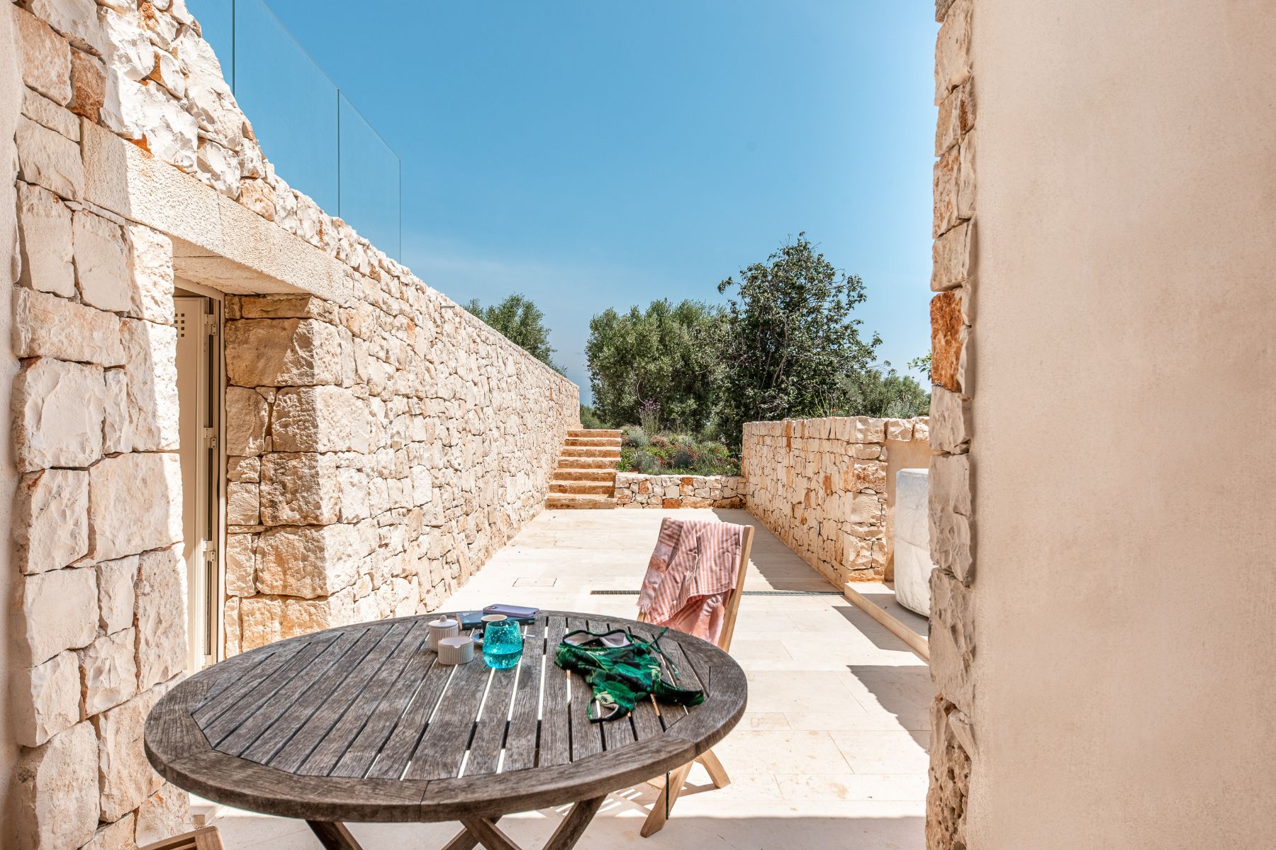 Outdoor patio from the bedroom at Villa Venere in Puglia with view of stone walls and a wooden table and chair