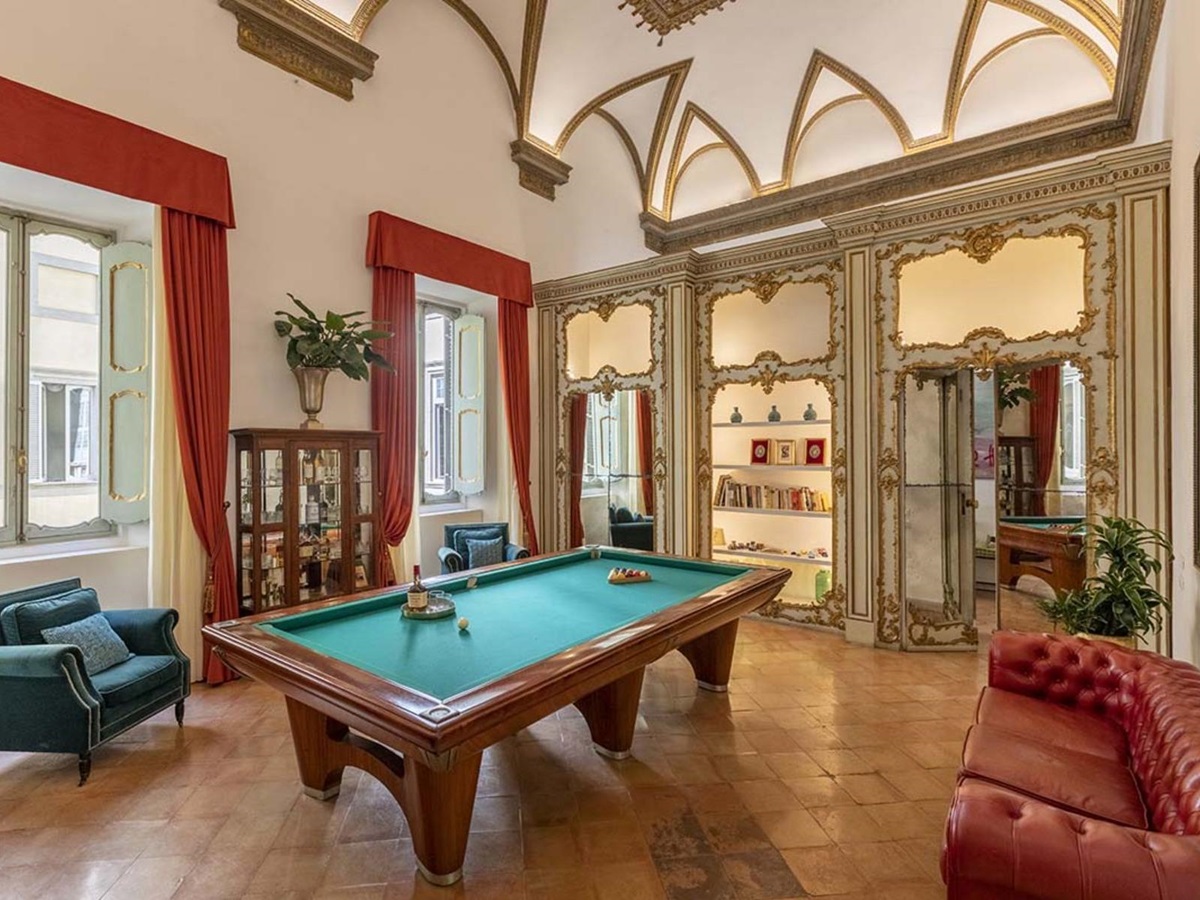 Billiard room at the Costaguti Apartment in Rome featuring a pool table in the middle and sofas at the side of the room