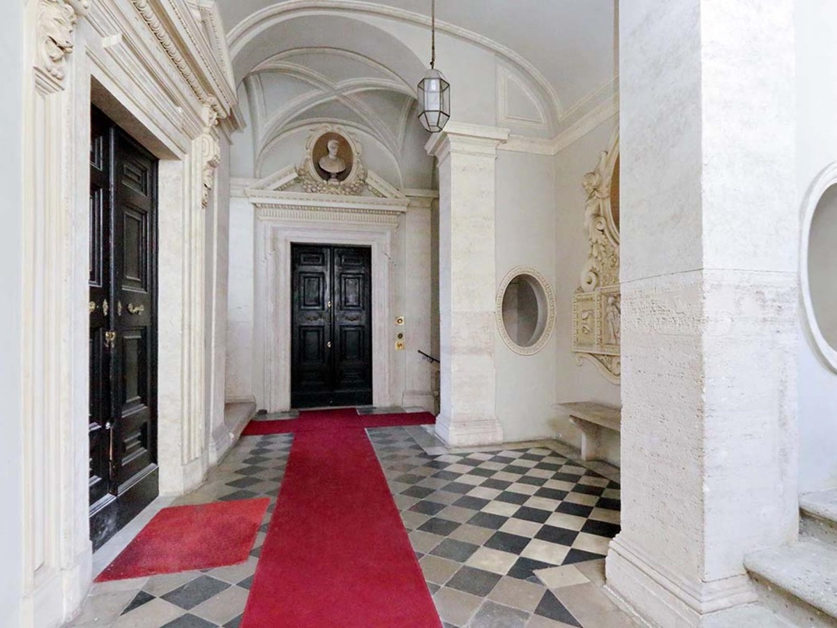 View of the entrance lobby at the Costaguti Apartment in Rome featuring marble floors and large black doors