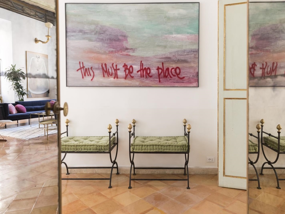 hallway with two cushioned stools and artwork at costaguti apartment, Rome