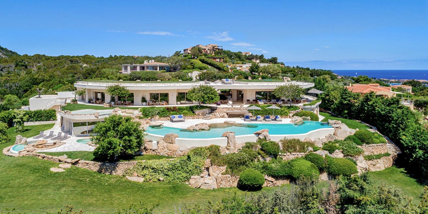 Large villa with pools and gardens in the foreground and sea on the horizon at The Rock in Sardinia