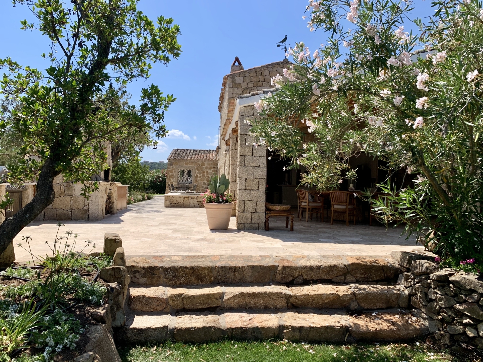 Garden with oleander, trees, cactus and outdoor dining areas at Villa Pantaleo on Sardinia, Italy
