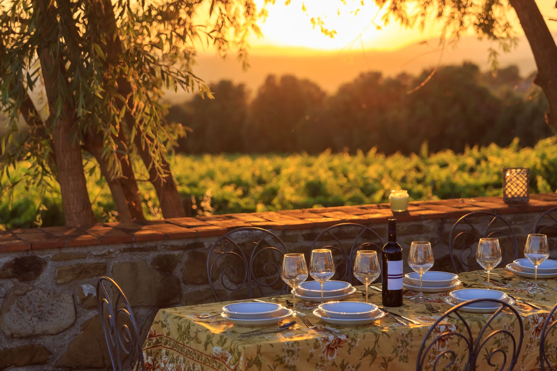 A table set for dinner at sunset looking out to Tuscan vineyards