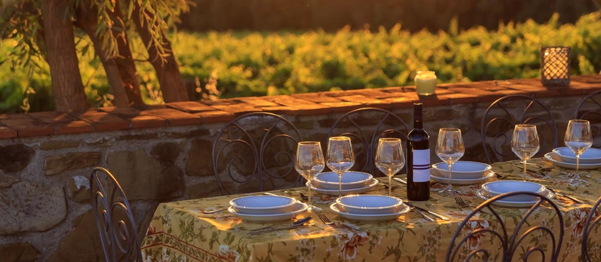 A table set for dinner at sunset looking out to Tuscan vineyards