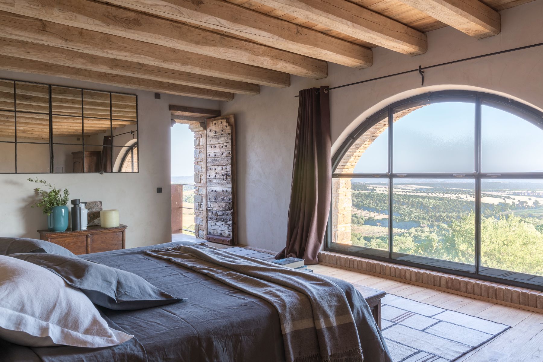 Bedroom with arch window view at Borgo Rinato in Tuscany