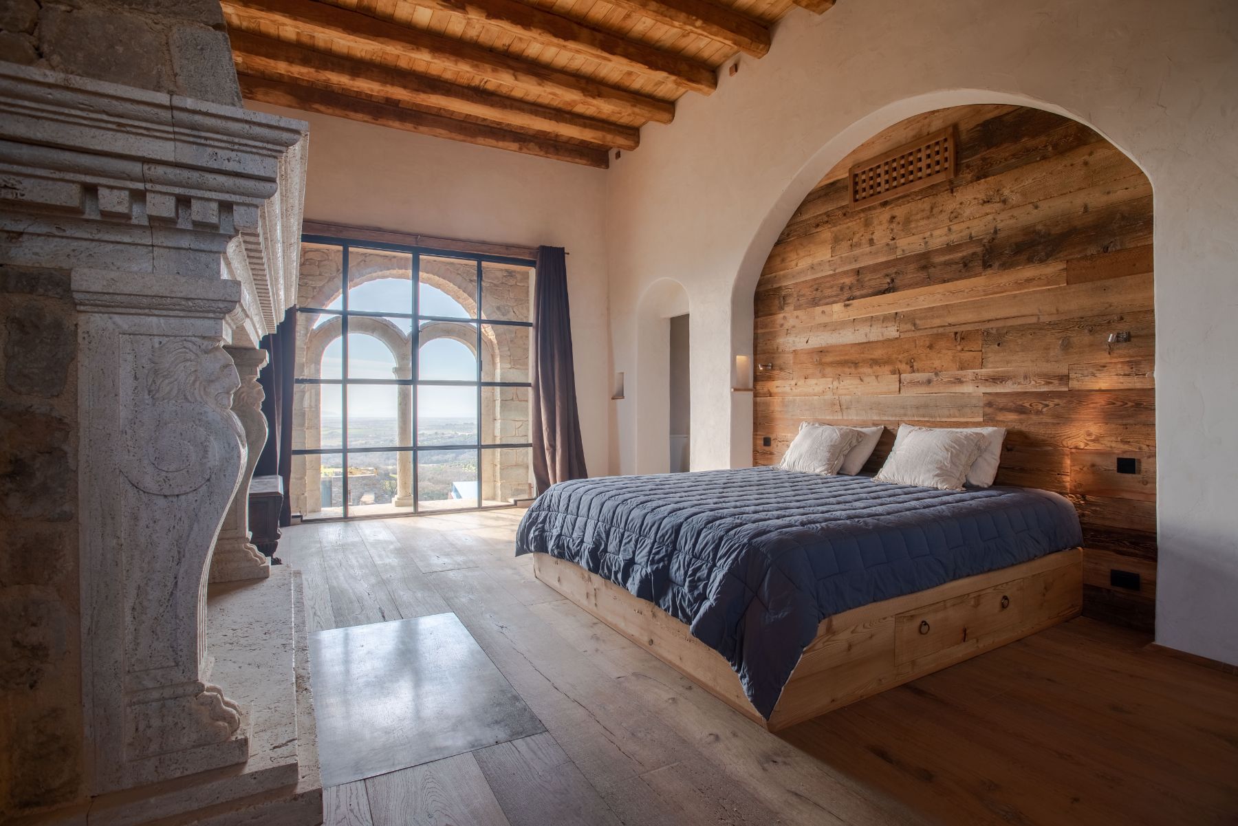 Bedroom with grey duvet and wooden headboard at Borgo Rinato in Tuscany