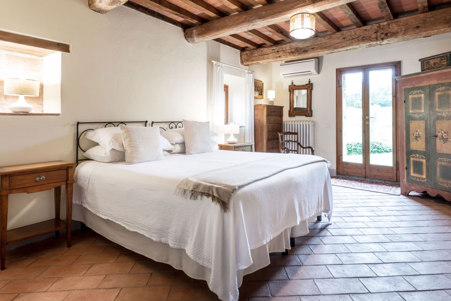 White and wooden bedroom at Casa Picchio in Tuscany