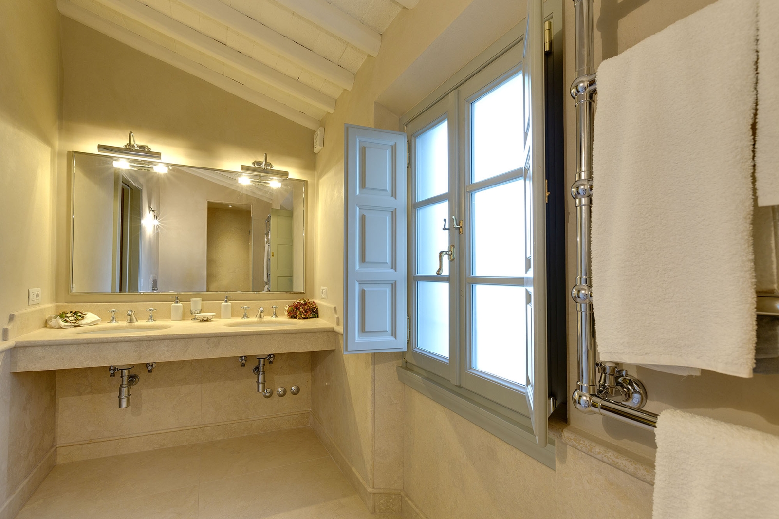 Bathroom with sinks, large mirror, large window, towels and towel rail at Castel Botticelli in Tuscany, Italy