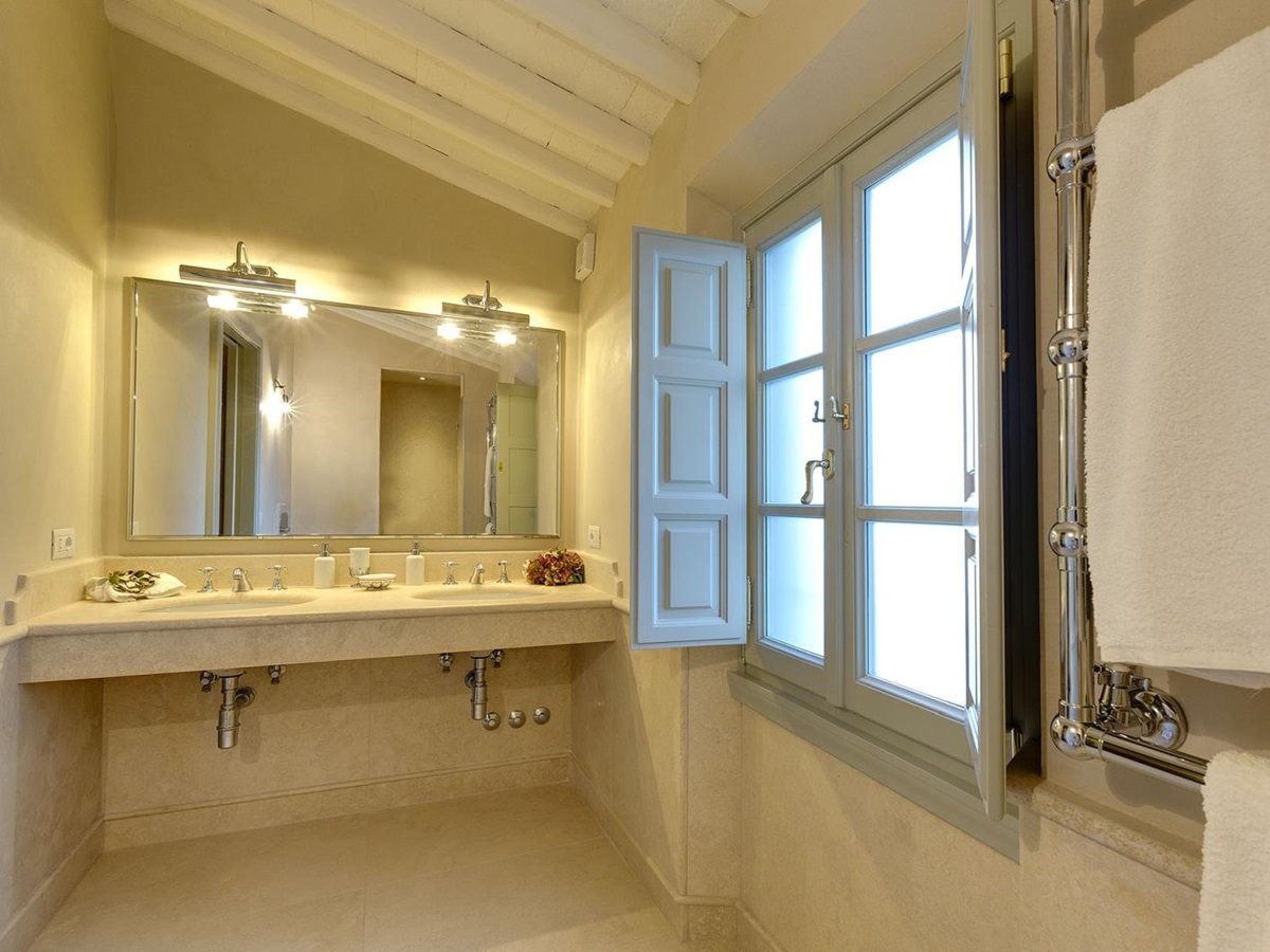 Bathroom with sinks, large mirror, large window, towels and towel rail at Castel Botticelli in Tuscany, Italy