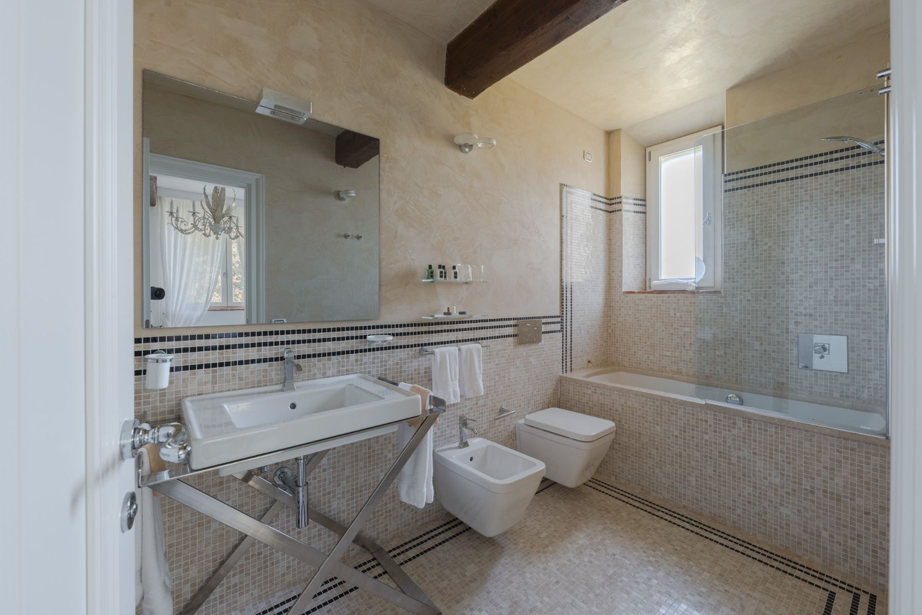 Bathroom with beige tiles and bath tub in Villa Il Mugnello in Tuscany