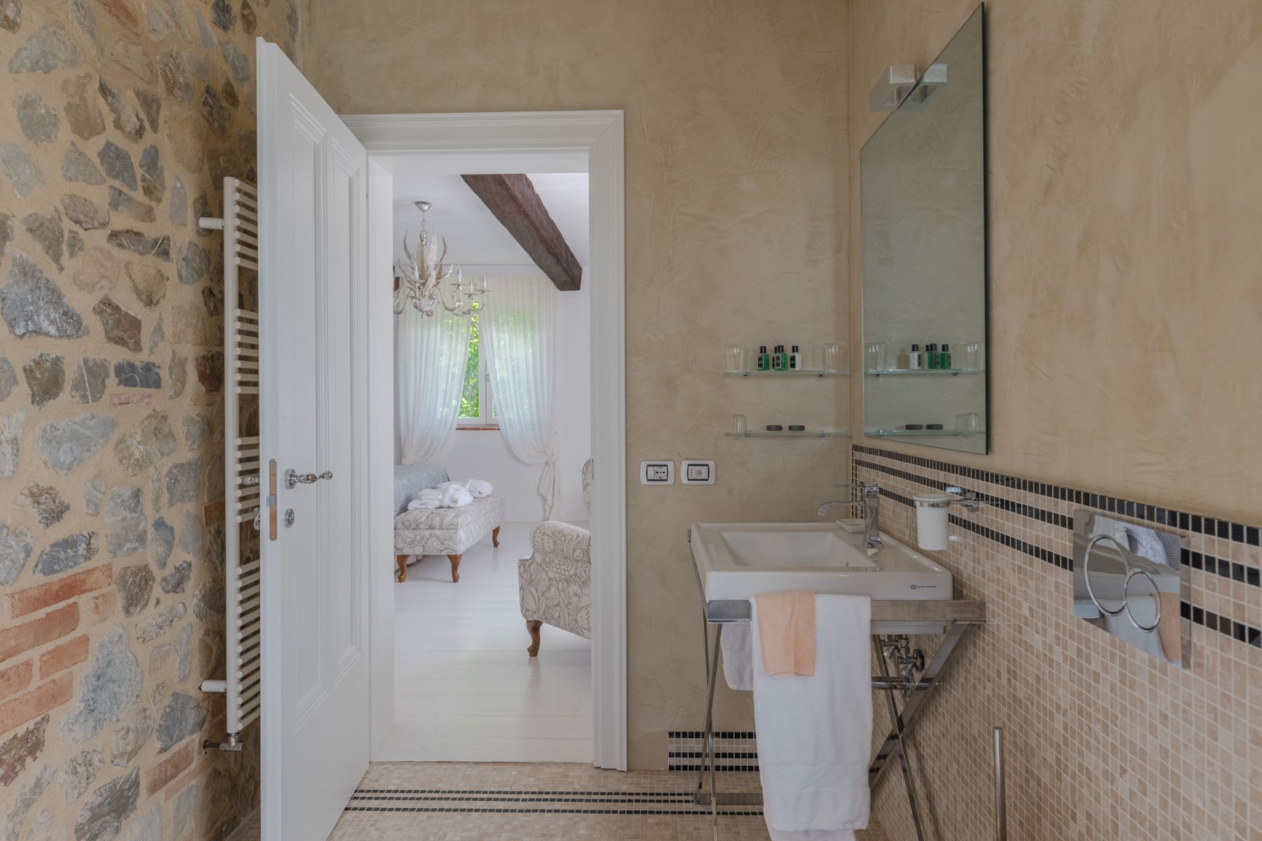 Bathroom with white door open with view into the bedroom at Villa Il Mugnello in Tuscany