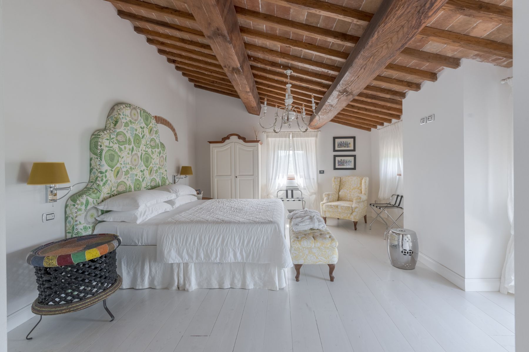 Bedroom with large double bed and green headboard in Villa Il Mugnello in Tuscany