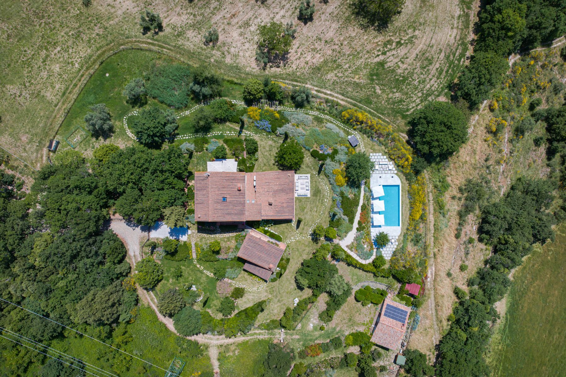Drone view of Villa Il Mugnello in Tuscany with view of the property and the pool surrounded by fields