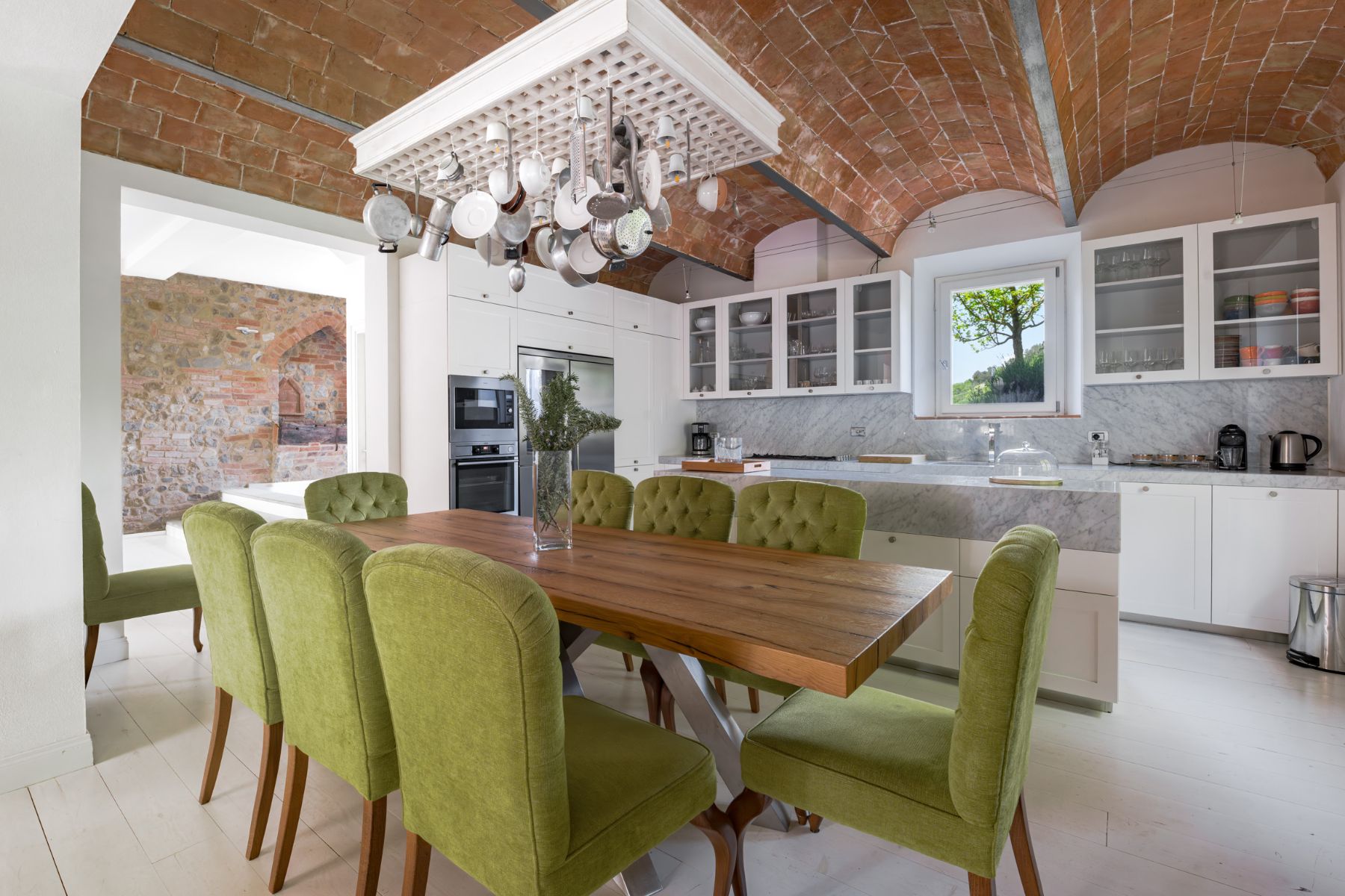 Indoor dining area next to the kitchen, featuring wooden dining table with green chairs