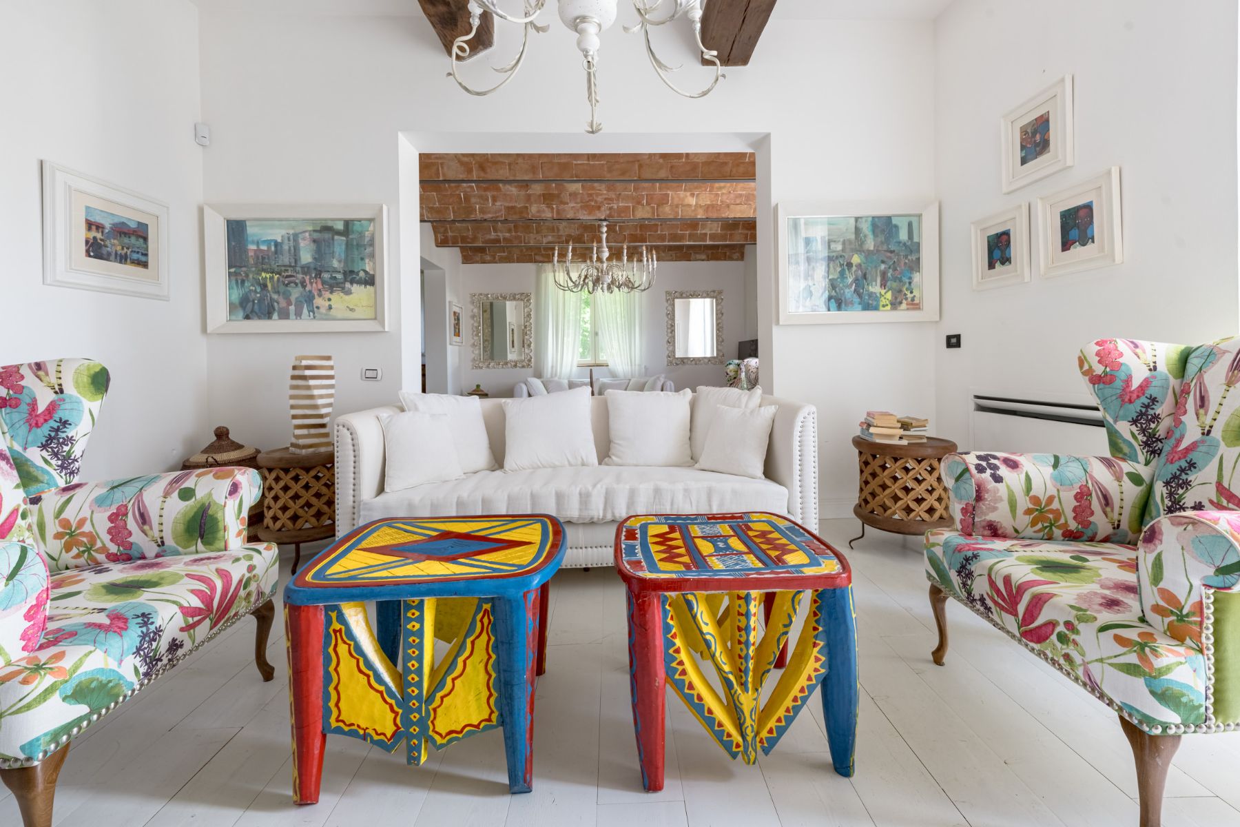 Living area with colourful coffee tables featuring armchairs and a white sofa in Villa Il Mugnello in Tuscany