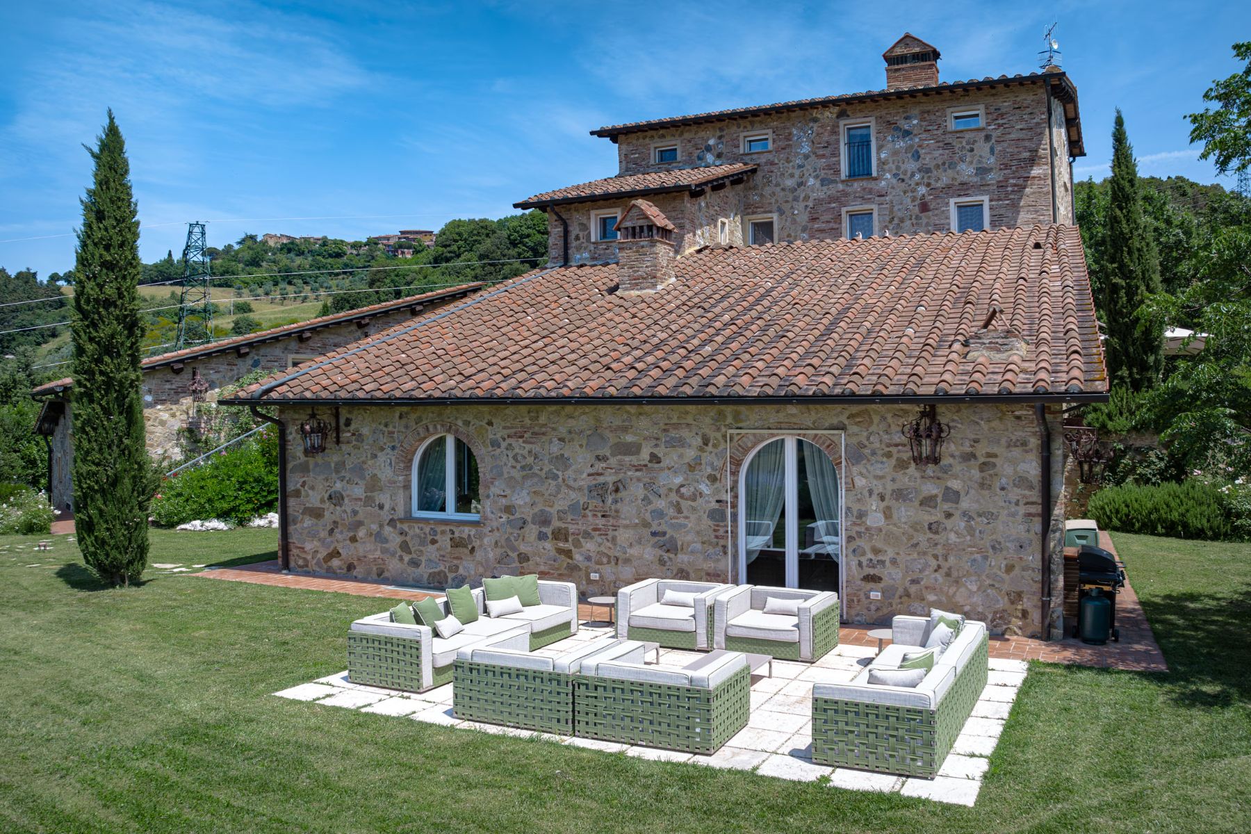 Outdoor seating area at the back of Villa Il Mugnello in Tuscany featuring white and green sofas