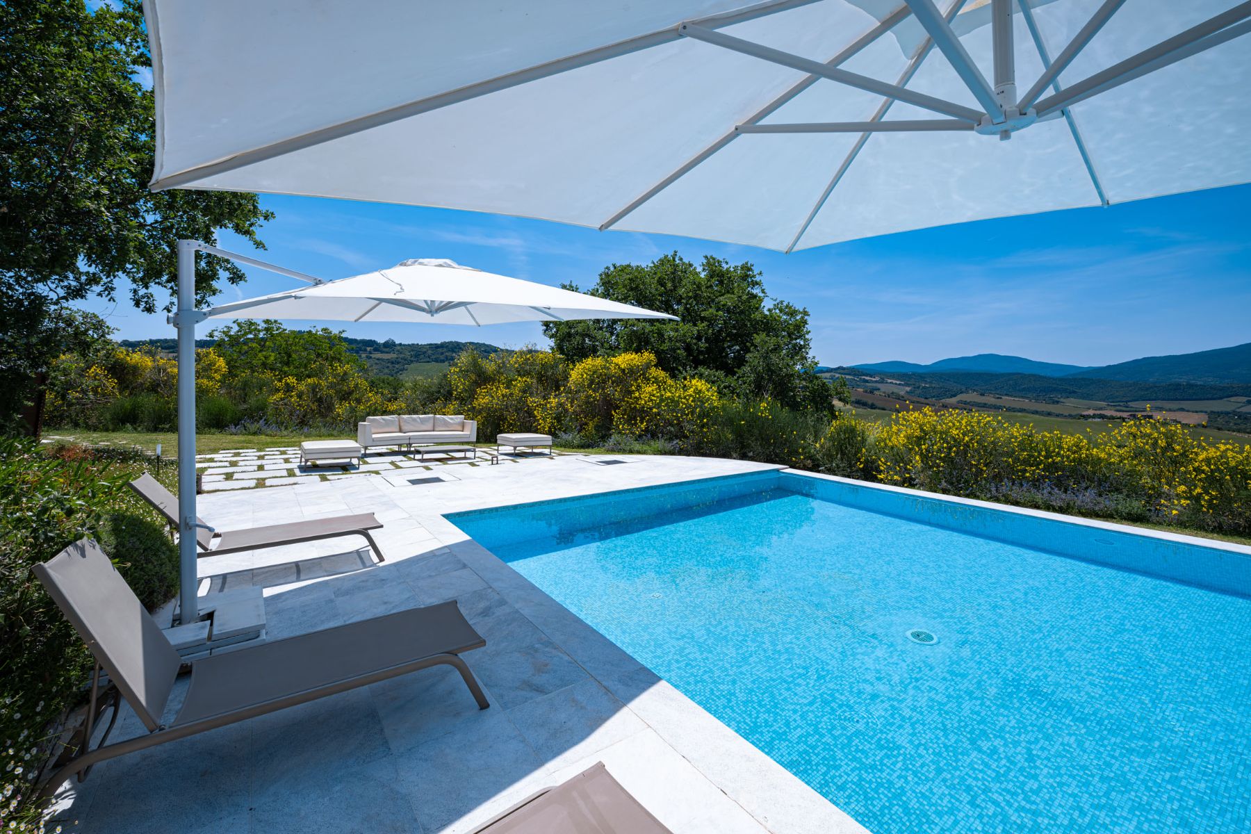 Up close view of the pool underneath an umbrella next to the sun loungers at Villa Il Mugenllo in Tuscany