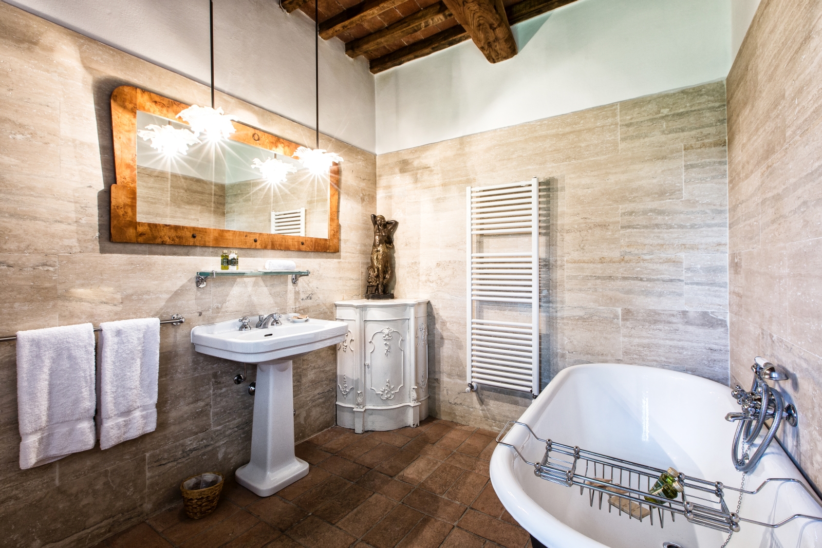 Bathroom with bath, towel rail, cabinet, bronze statue, sink and mirror at Il Prato di Vignamaggio in Tuscany, Italy