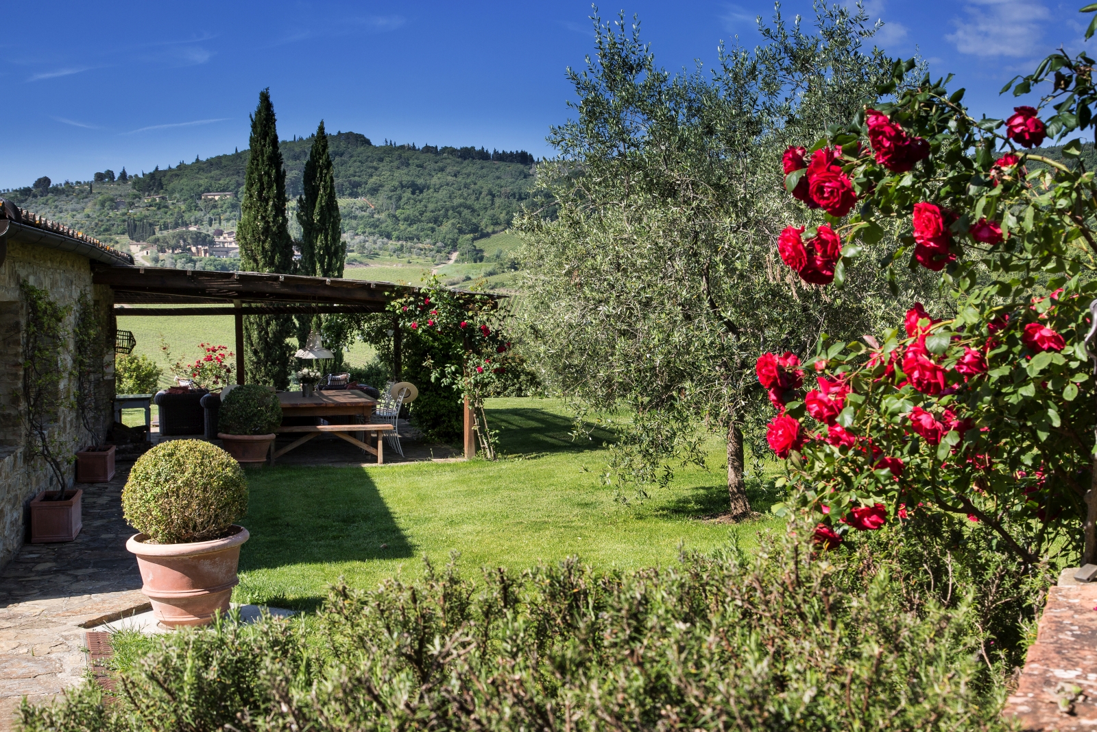 Garden with plants, flowers, covered terrace and view of countryside at Il Prato di Vignamaggio in Tuscany, Italy