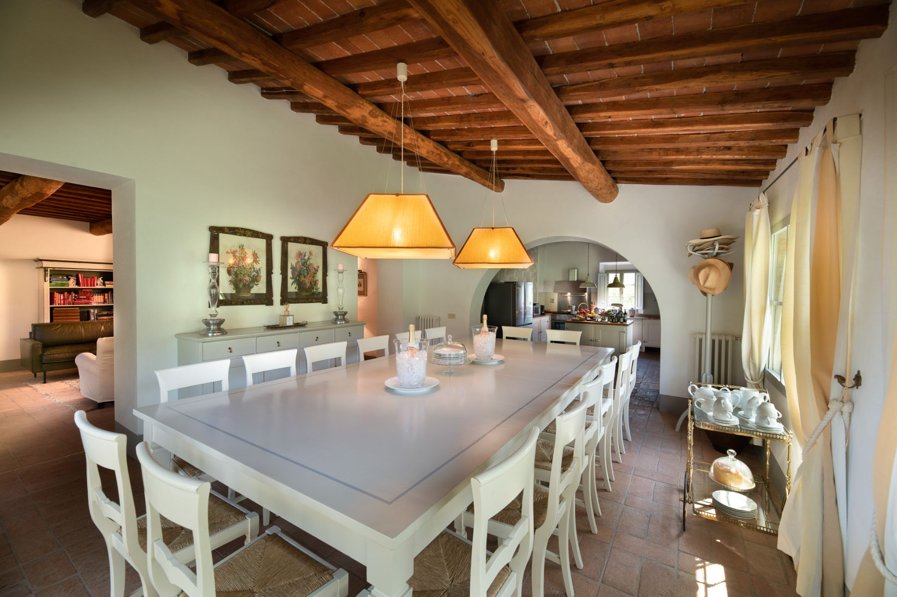 Dining room with a long white table in the middle of the room with white chairs at Il Prato di Vignamaggio in Tuscany