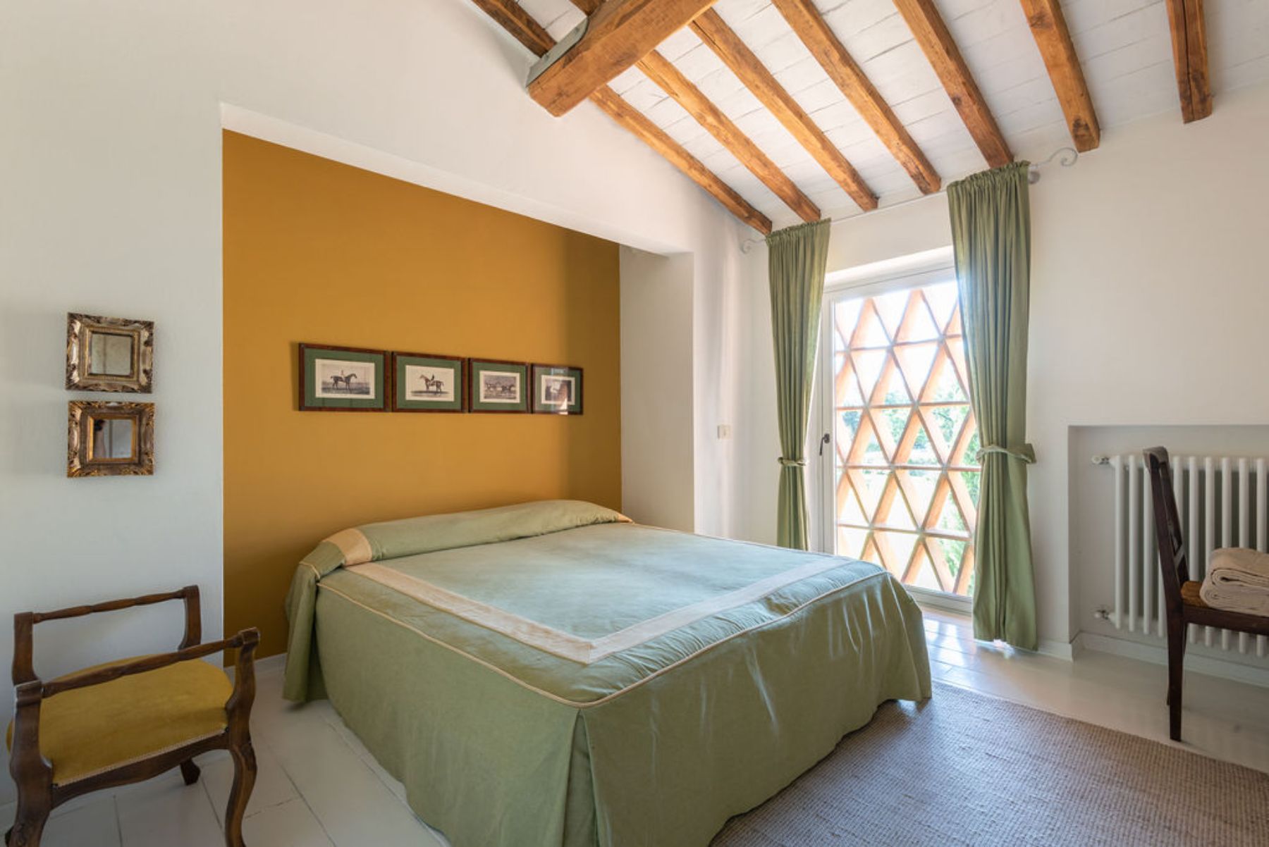 Bedroom with double bed and green bedding and curtains with a yellow wallpaper at Il Prato di Vignamaggio in Tuscany