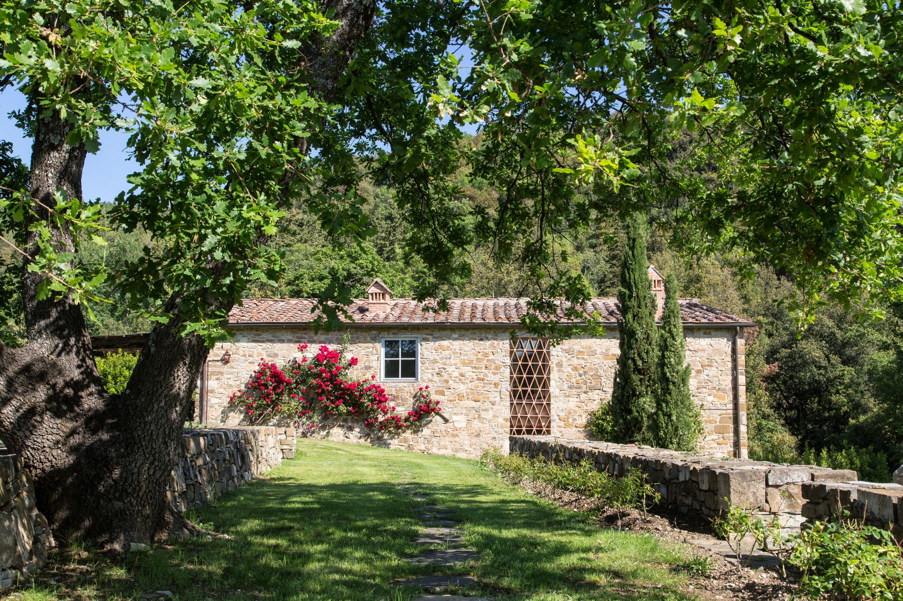 Fenile building made of stone from the garden surrounded by trees and flowers at Il Prato di Vignamaggio in Tuscany