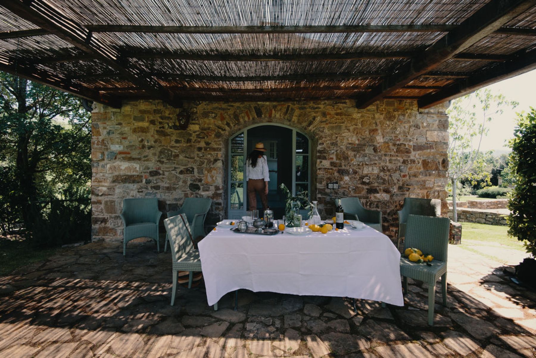 Outdoor dining area with a white table and green chairs in front of the Fenile building at Il Prato di Vignammagio in Tuscany