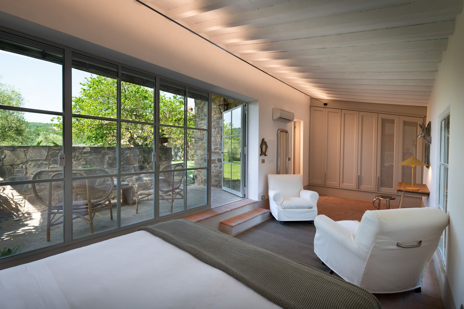 Modern studio bedroom with white arm chairs and an outdoor terrace at Il Prato di Vignamaggio in Tuscany