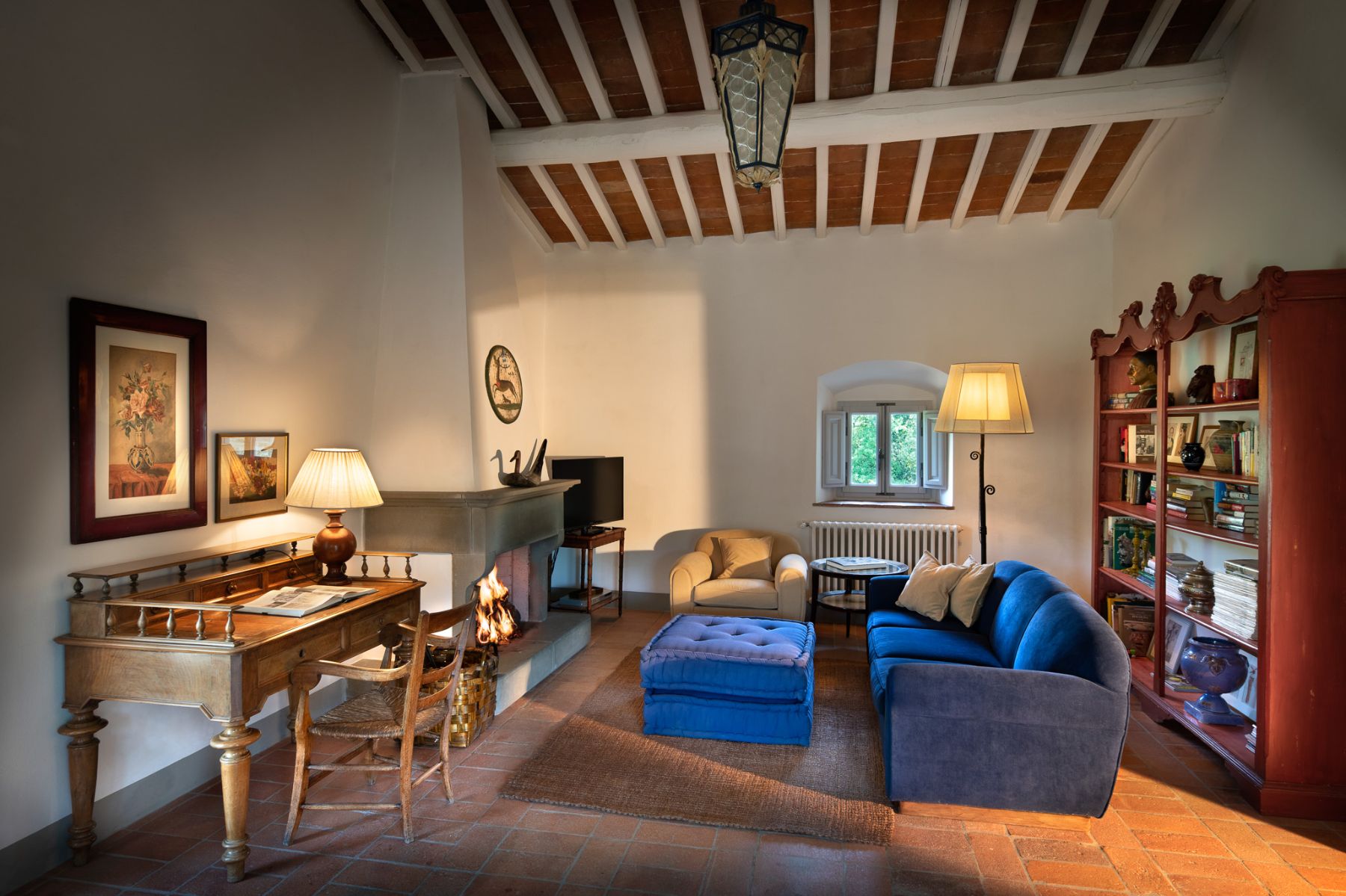 Living room in the cottage at Il Prato di Vignamaggio with a blue sofa and wooden desk in Tuscany