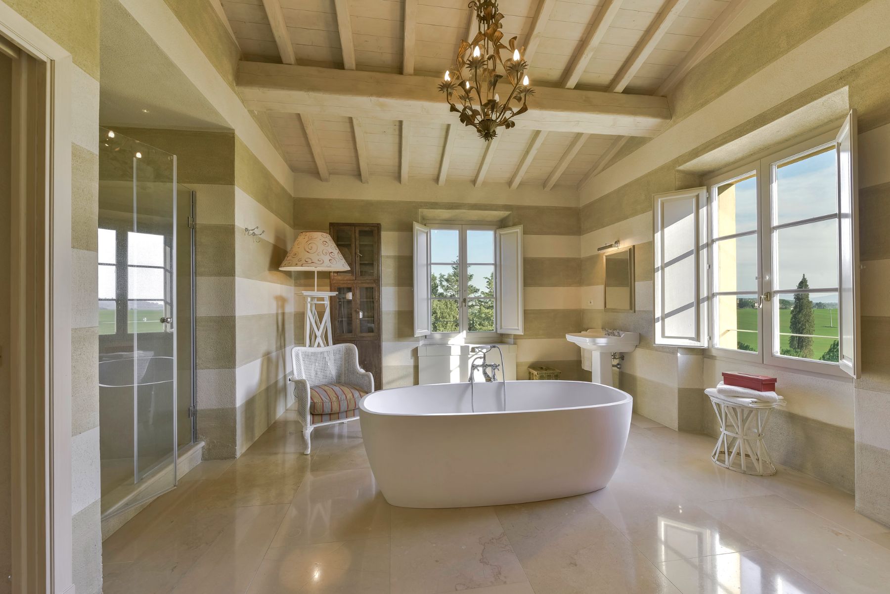 bathroom with large white bath tub in the middle of the room and chandelier on the ceiling