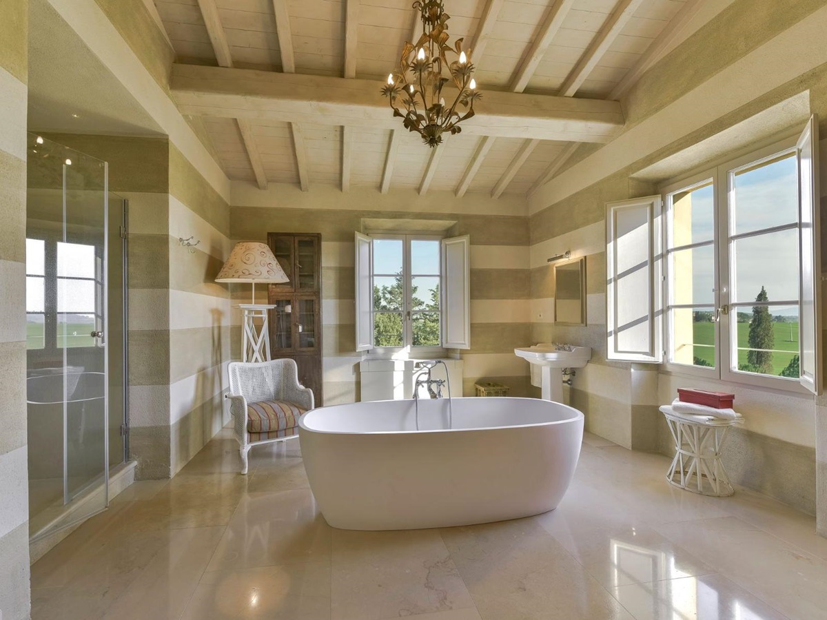 bathroom with large white bath tub in the middle of the room and chandelier on the ceiling