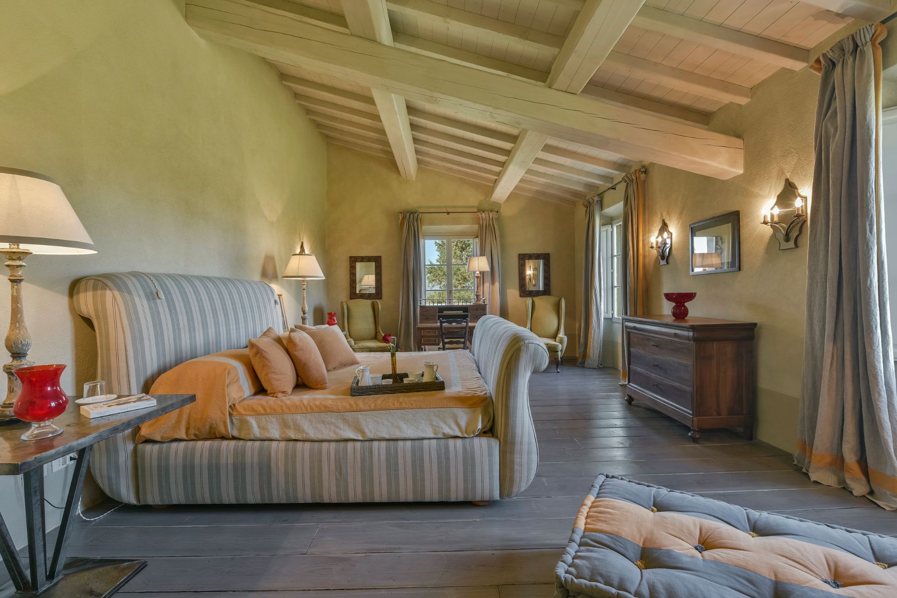 Bedroom in villa Il Serratone in Tuscany, with large striped bed and chest of drawers