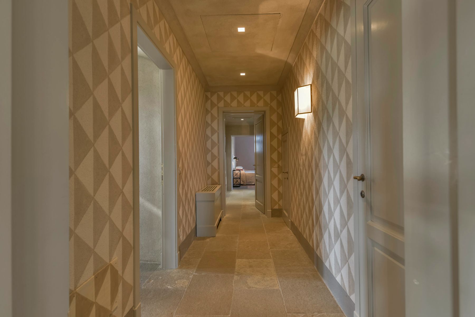 Corridor at villa Il Serratone in Tuscany with patterned wallpaper and rooms each side