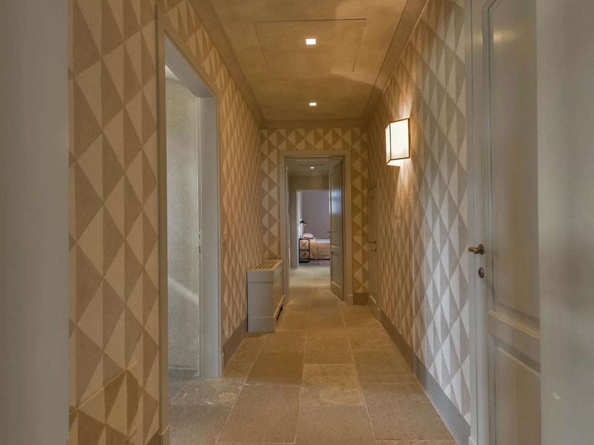 Corridor at villa Il Serratone in Tuscany with patterned wallpaper and rooms each side