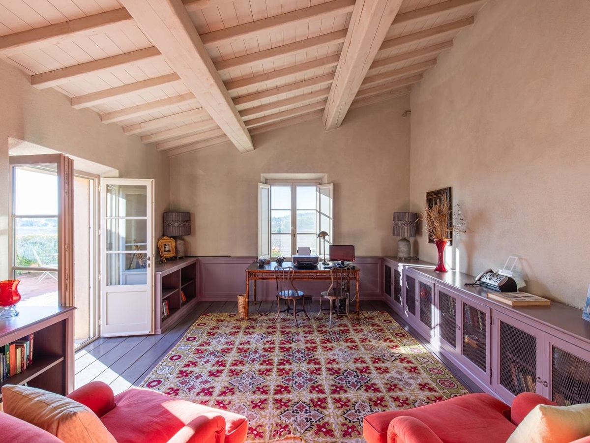 Study with armchairs, bookshelves, desk, chairs, lamps and French doors at Il Serratone in Tuscany, Italy