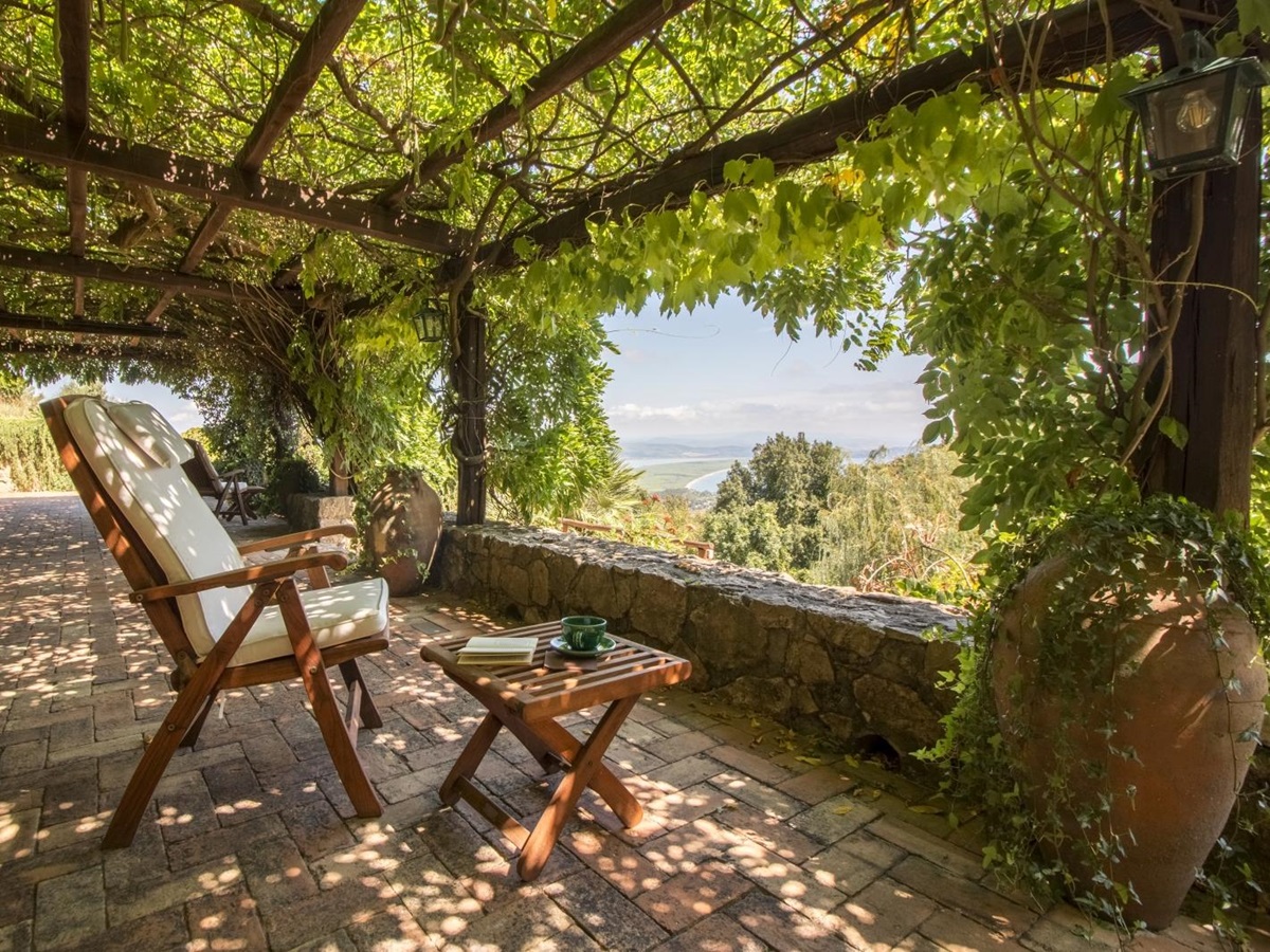 Terrace with chairs, coffee table, vines and sea view at La Feniglia in Porto Ercole in Tuscany