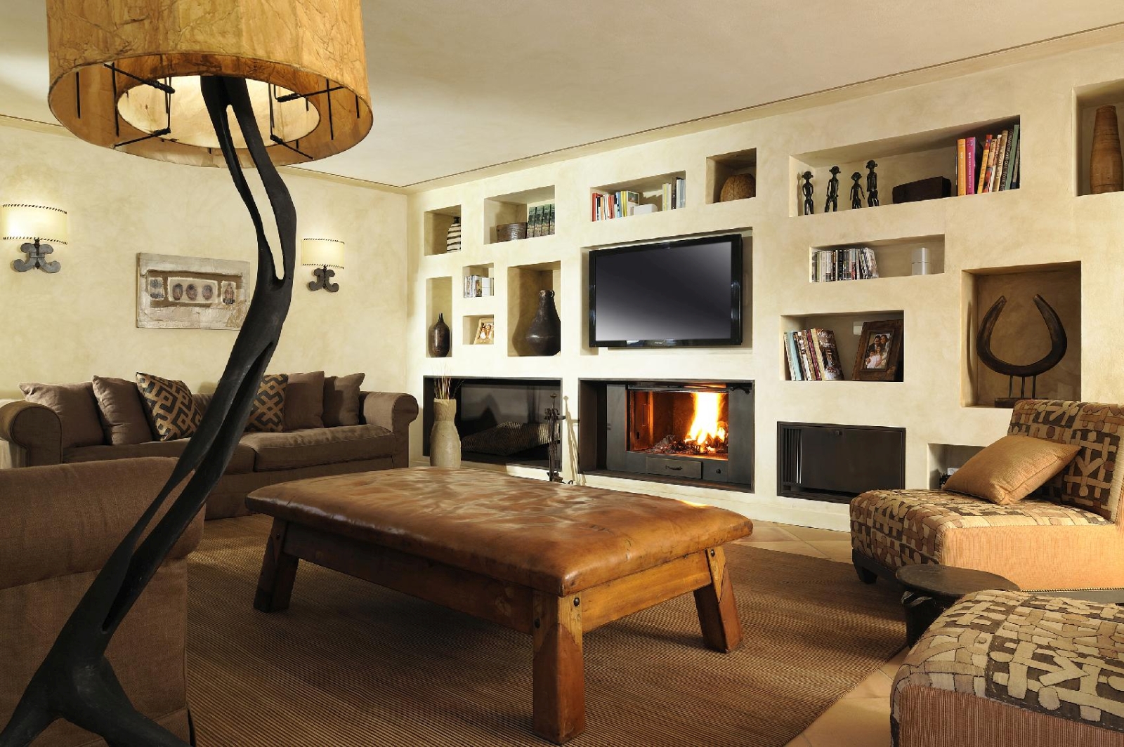 Living room with lamp, bookshelves, TV, sofas, armchairs and fireplace at La Feniglia in Porto Ercole, Tuscany